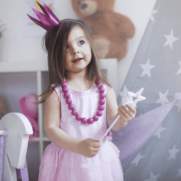 a child in a pink dress holding a magic wand