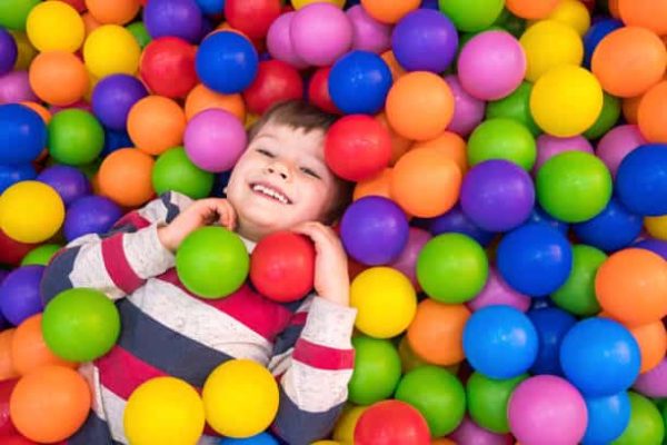 Little boy playing in dry pool with plastic balls in the nursery. Close-up leisure activities indoors. Positive emotions background. School holidays. Copy space